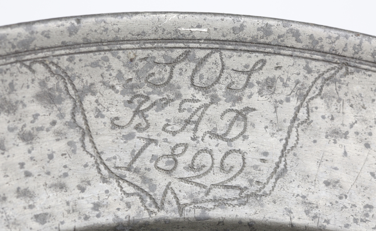 Fat av tenn.
Runt, hamrat stekfat. Brämen avslutas med rundstav. På brämens ytterkant finns två graverade monogram inom en bård: "S.O.S., K.A.D., 1822". På brämens undersida finns graverat ägarinitialer: "I.V.R.". Stämplar på brämens översida.

Inskrivet i huvudbok 1886.
