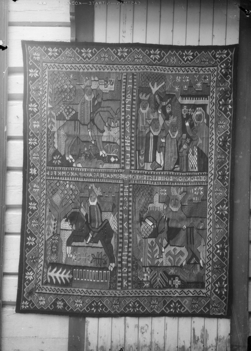Billedvev, teppe med fire motivbilder av de Hellige tre konger. Skrift i kryss mellom bildene.