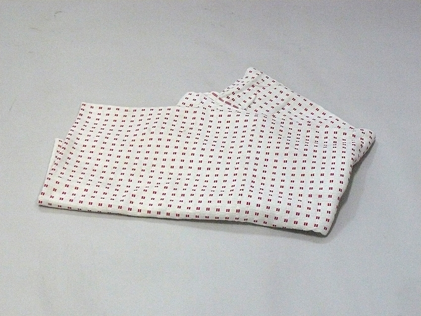 Överkast i rödvitt-mönstrad hemvävt bomullstyg. Hopskarvat av två bitar med söm. Har vävts och använts av eleverna på Omsorgsförvaltningen Sandbäck i Norrköping.