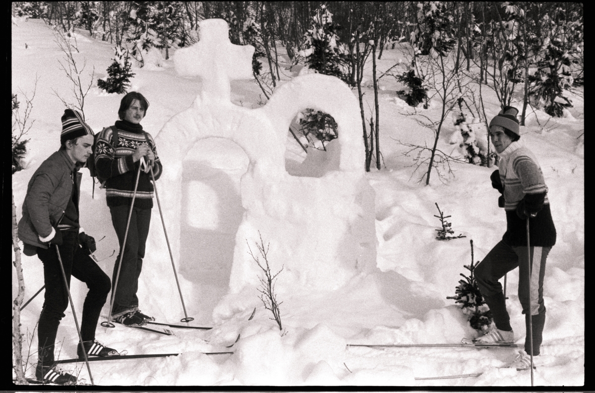 Tre menn på ski foran "snøskulptur".