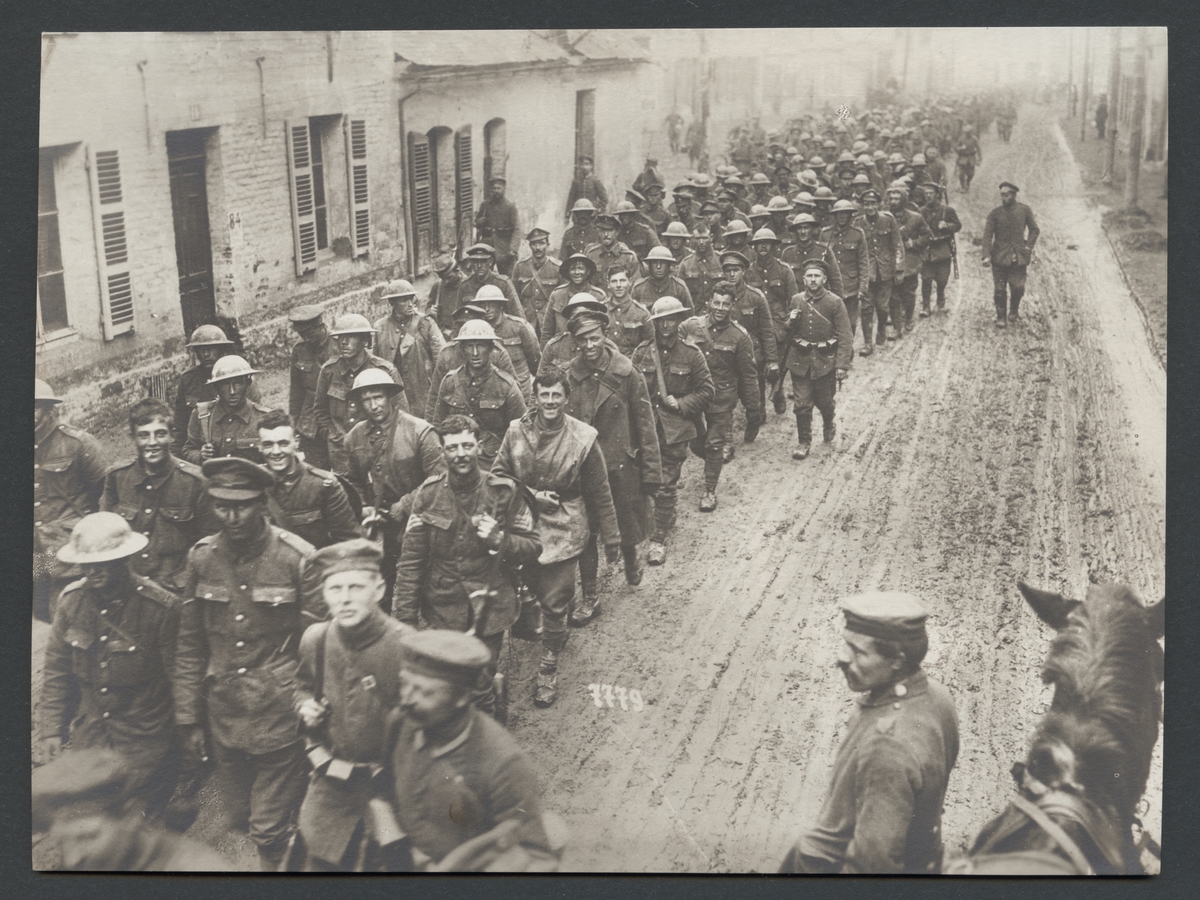 Bilden visar tillfångatagna engelska soldater som marscherar på en slamtäckt gata genom en fransk by.

Originaltext: "De första masstransporterna av vid genombrottslaget tillfånga-
tagna engelsmän, anlända till en ort söder om St. Quentin."