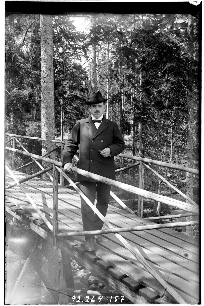 Hålahult sanatorium, exteriör, en man på en träbro i skogen klädd i kostym och hatt cigarr i handen, underläkare N.G.K. Lewenhagen 1/10 - 31/10 1916?