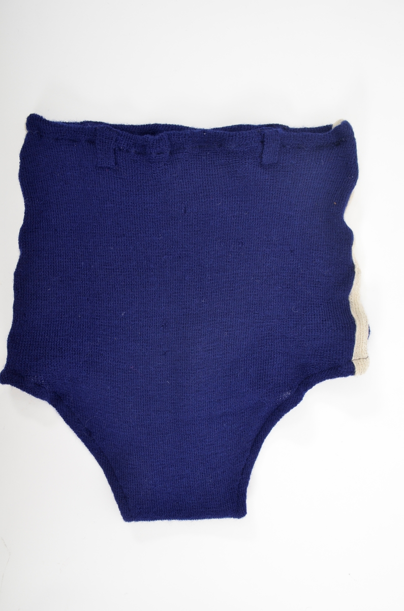 Bukse, badebukse ribbestrikka i blått ullgarn med kvite striper i sidene. Smettestolar og løpegang med strikk i livet. Dobbel framme (same tøyet).