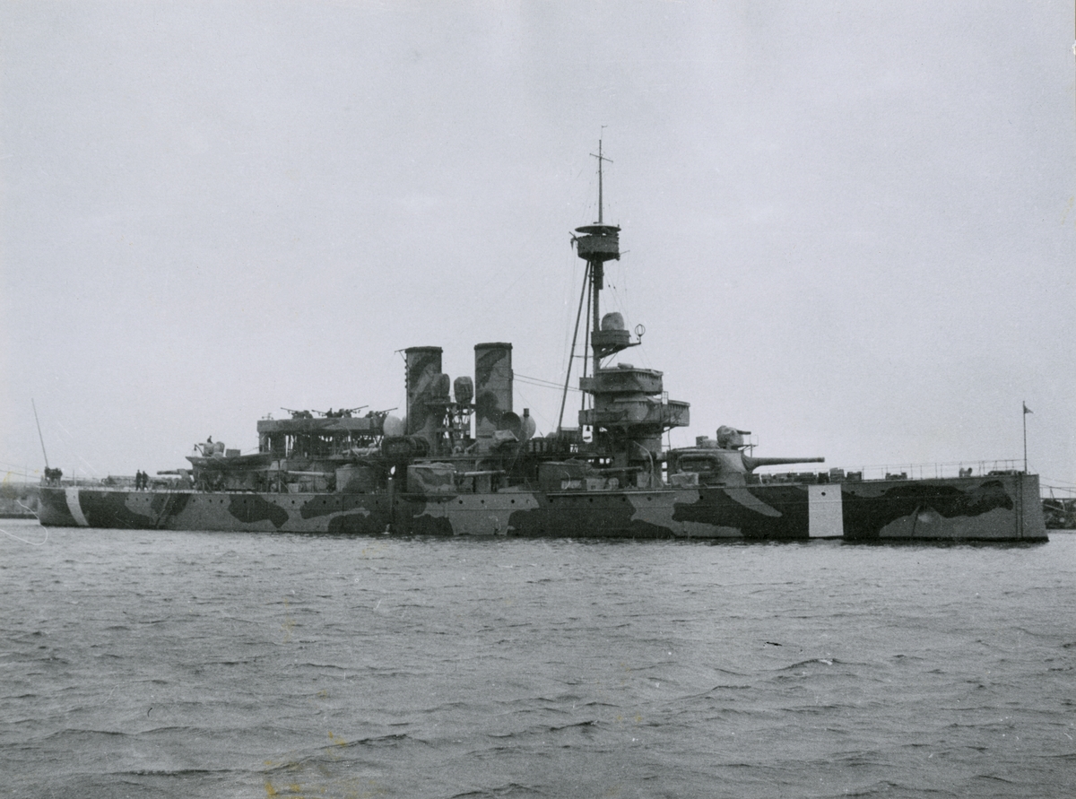 Pansarskeppet ÄRAN i kamouflagemålning och med vit neutralitetsrand på skrovsidan.