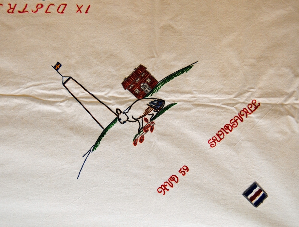 Duk, broderad av det s.k. Kvinnorådet inom JHF (Järnvägsmännens Helnykterhetsförbund), i stjälksöm och dubbelsidig plattsöm med färgat garn på vitt bomullstyg.

Motiv med symboler från fyra olika avdelningar. I mitten står "IX DISTRIKTET 1961-1970".
Hörn 1: "AVD 59 SUNDSVALL", medelpads landskapsvapen (blå, vit, röd, vit, blå rand), en skvader (ett fantasidjur vars framdel är en hare och bakdel en tjäder, djuret är en inofficiell symbol för Sundsvall) samt en byggnad från friluftsmuseet på norra berget och utkikstornet "Glasspinnen" på samma plats. 
Hörn 2: "AVD 105 HÄRNÖSAND", ångermanlands landskapsvapen (tre fiskar samt krona på toppen av skölden), styvmorsvioler (landskapsblomma).
Hörn 3: "AVD 104", "1981", motiv av föreningslokalen Storvallen i Storlien utanför Östersund, brunkulla (landskapsblomma), guckusko (vanligt förekommande orkidé i Jämtland) samt hjortron.
Hörn 4: "AVD 58 ÅNGE", "MUNKBYSJÖN - SVERIGES MITTPUNKT", grankottar (Medelpads landskapsblomma) samt en kaducé med bevingat hjul (SJ:s symbol).