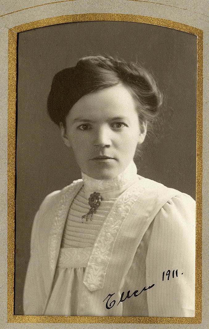 En ung kvinna i ljus blus med hög krage. En brosch syns vid kragen. I nedre högra hörnet finns autograf: "Ellen, 1911". 
Midjebild, halvprofil. Ateljéfoto.

Jfr Alb7-024.