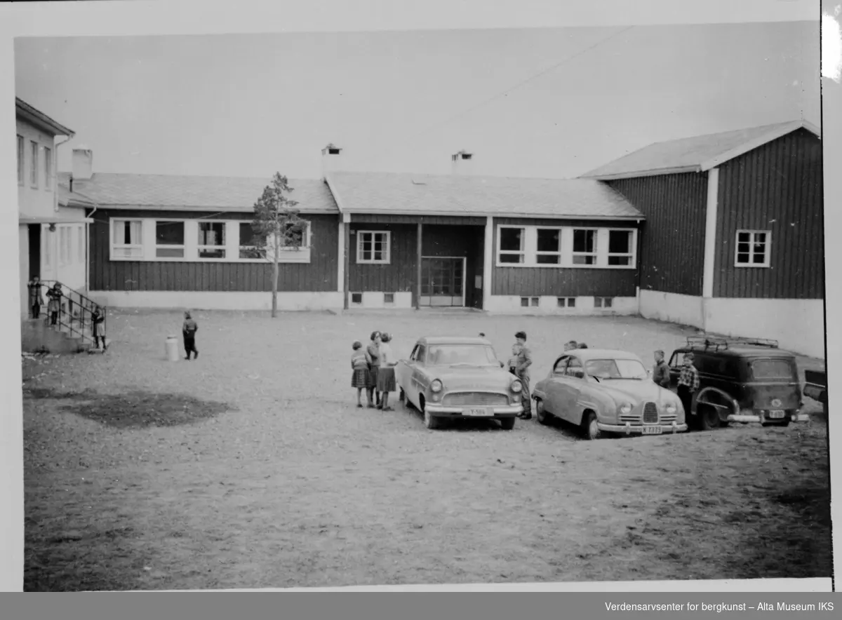 Skole med barn og tre biler parkert utenfor