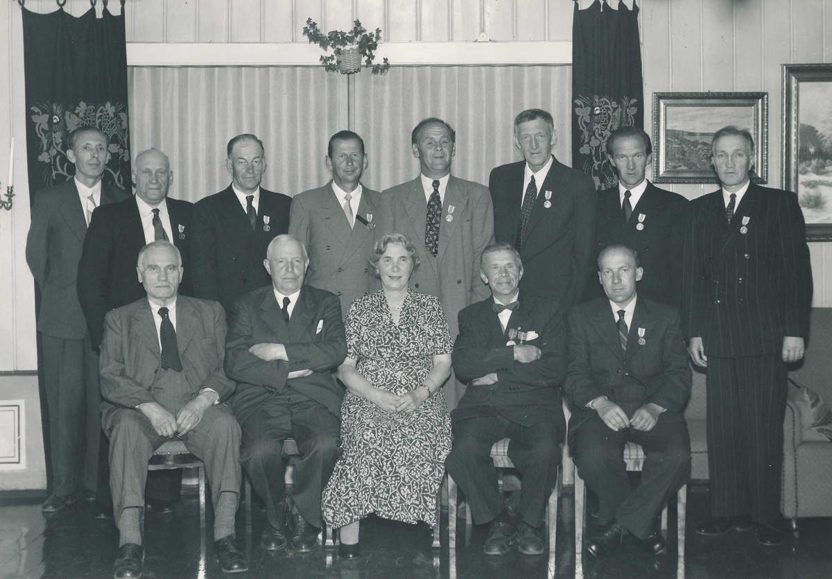 Gruppebilde med en kvinne og 12 menn i forbindelse med at 8 av mennene har fått utdelt Det Kongelige Selskap for Norges Vels medalje for lang og tro tjeneste.