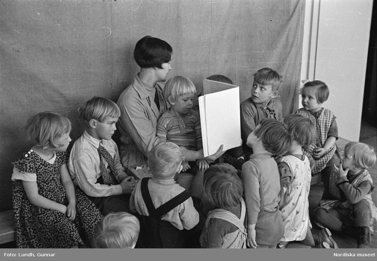 Motiv: H.S.B.s lekstuga på Skeppargat. (gärdet) (Skeppargatan) (HSB);
Vy över odling med drivbänkar, barn och vuxna på en lekplats, exteriör av hyreshus, barn leker vid ett bord och får instruktioner av en kvinna, barn håller i en modellbåt, ett barn sitter på en gunghäst.

Motiv: H.S.B.s lekstuga på Skeppargat. (gärdet) (Skeppargatan) (HSB);
En kvinna håller upp en texkning för en grupp barn.