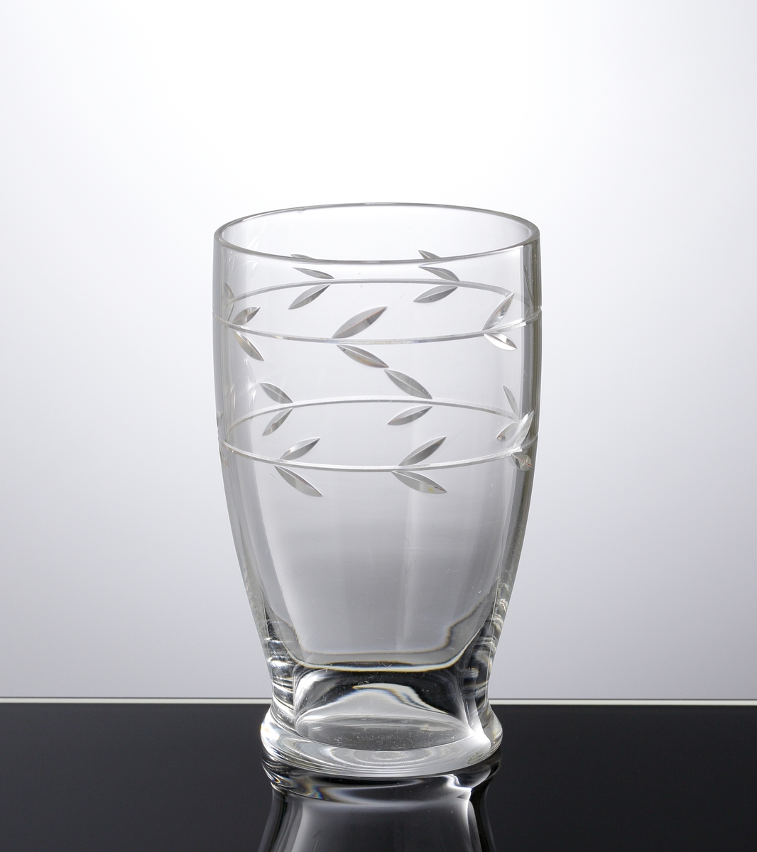 Dricksglas i ofärgat klarglas med slipad dekor i form av två ringar med bladpar som löper runt flaskan.