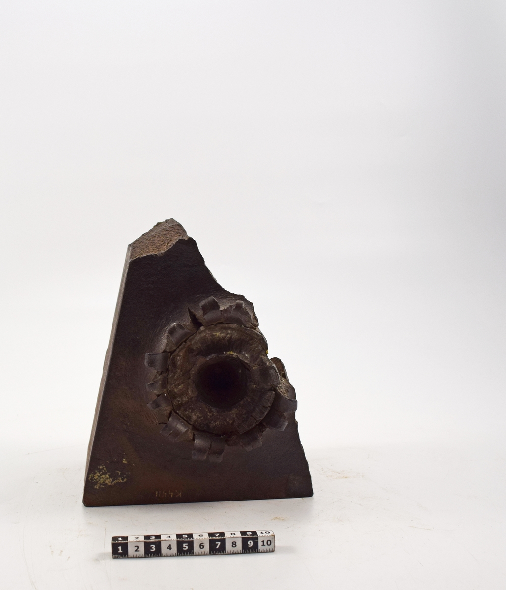 Plåt av stål, 12 cm, triangelformad. Plåten har tillhört en plåt använd  vid provskjutning, varvid spetsen av projektilen trängt in till ett djup av 70mm, där den blivit avskuren och kvarsittande.