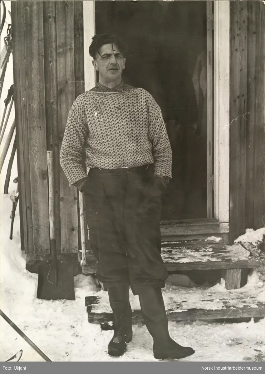 Jon O. Vågen med gummistøvler står i snøen utenfor åpen husdør