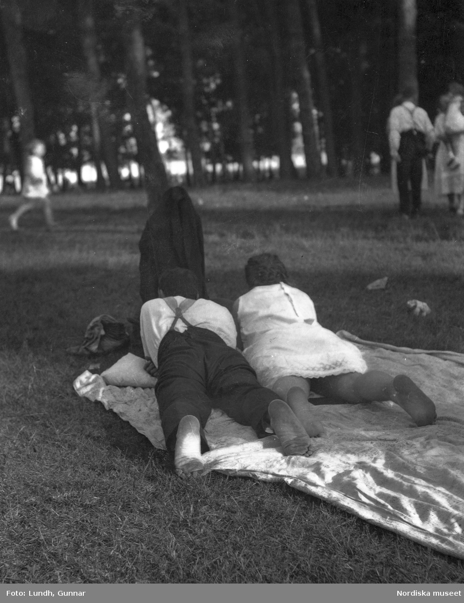 Motiv: Utlandet, Bad v. Berlin 147 - 156 ;
Vy över en badstrand med människor som sitter på marken och människor som badar , en man och en kvinna ligger på en filt i en park, anteckning på kontaktkarta 149 "Badande barn".