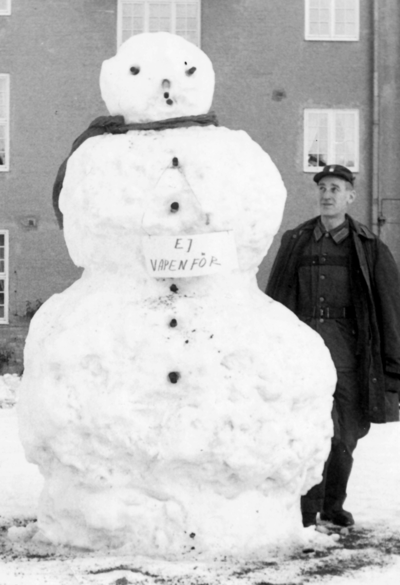 Vinterdag tidigt 1960-tal på kaserngården

En morgon när regementet vaknade stod denna snögubbe framför kanslihuset med texten "Ej vapenför" på det kalla bröstet.

Fanjunkare Arne Gustavsson betraktar/beundrar skapelsen.