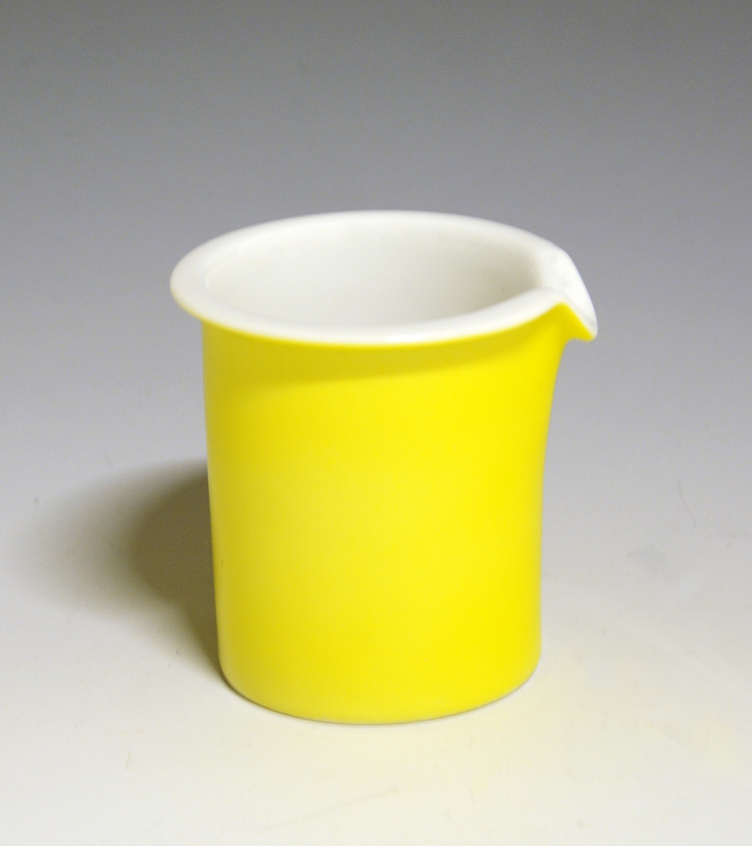 Fløtemugge av porselen. Hvit glasur. Uten hank. Heldekkende gult utvendig.
Modell: Saturn av Grete Rønning.
Dekor: Citron av Ferdinand Finne.