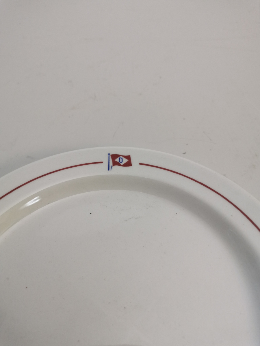 En 1mm rød kant, 0,9 cm fra ytterkant av tallerkenen med et mellomrom for rederiflagget til Ofotents Dampskibsselskap AS. Tallerkenkanten er 1,5 cm bred.