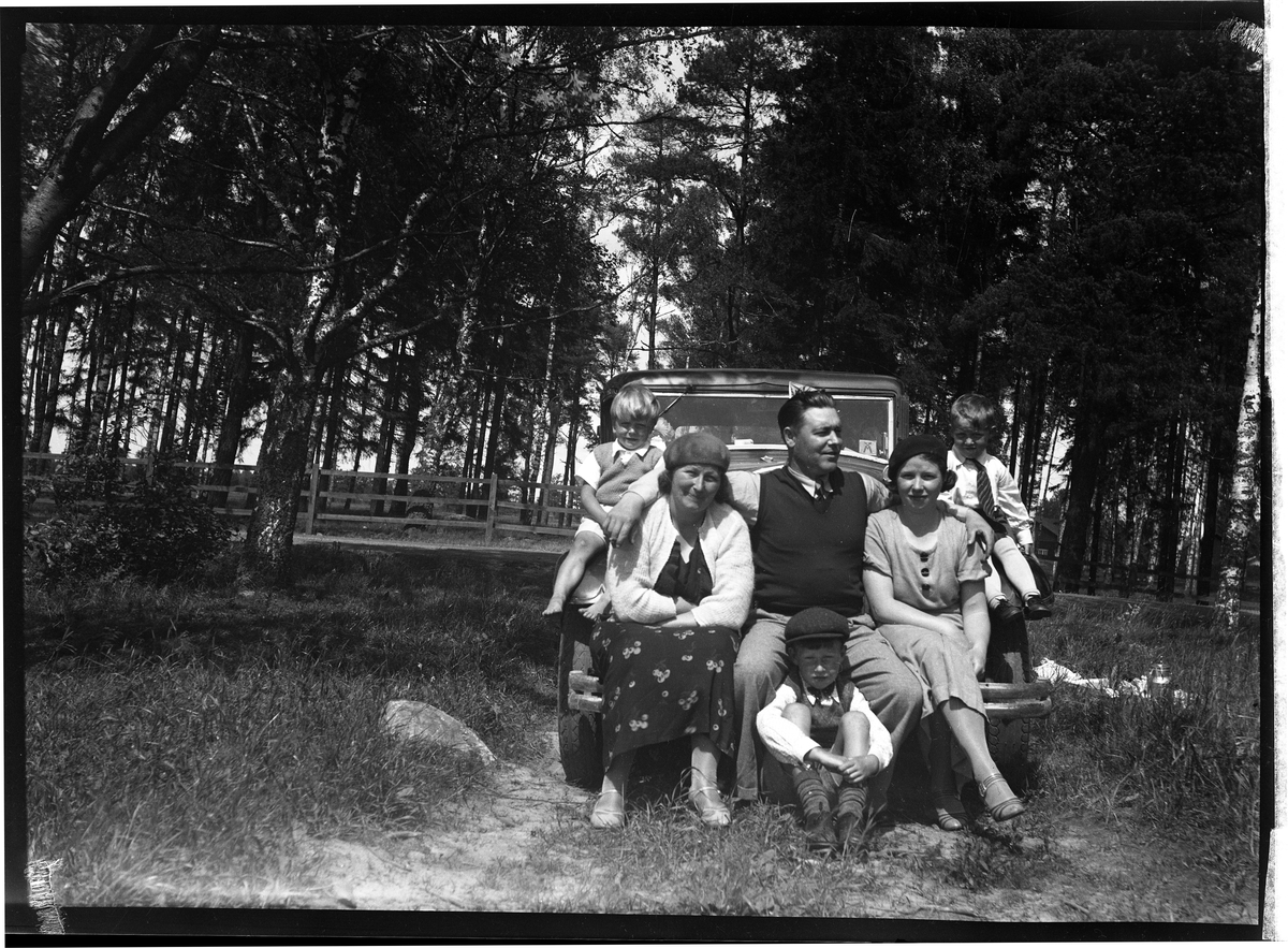 Gruppfoto av personer sittande vid och på en Volvo.