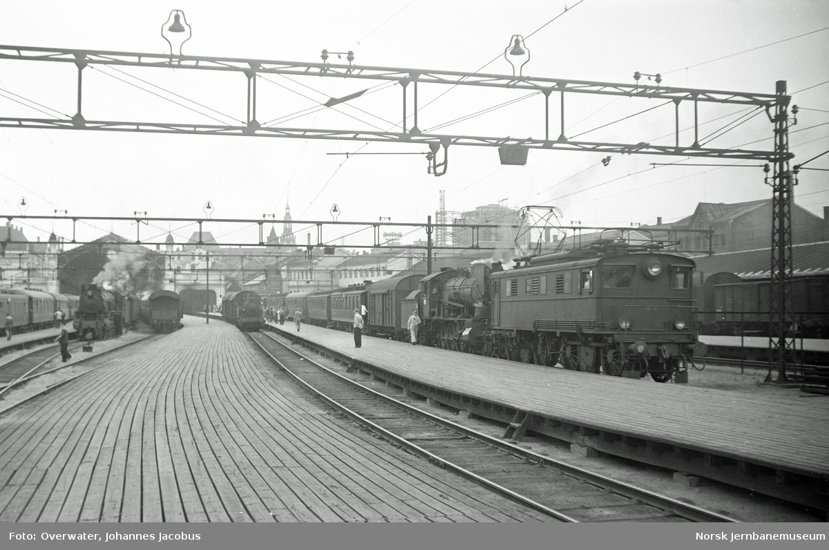 Elektrisk lokomotiv El 5 2035 som ekstra forspannlokomotiv i persontog til Trondheim, hurtigtog 1201, på Oslo Østbanestasjon. Til venstre damplokomotiv type 30b nr. 346 som forspannlokomotiv