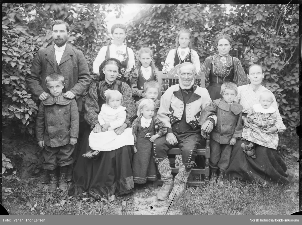 Gruppefoto. Eldre mann sittende på stol i bunad med barn rundt seg ...