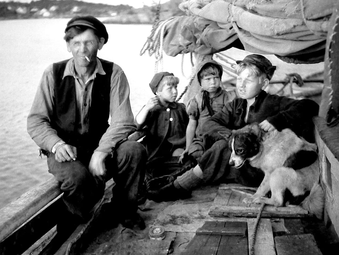 Tønnes Bredesen in his smack with three of his children. Taken in the Arendal area ca. 1947.