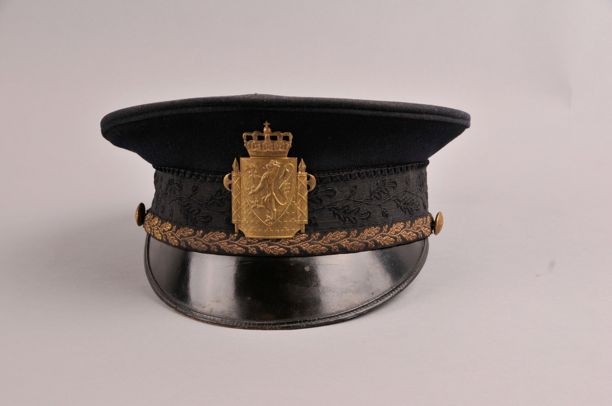Uniformslue, modell 1935, med fastsydd pull, stormsnor for politioverkonstabel, og høgare tjenestemenn. Luemerke med riksvåpen av modell 1937.