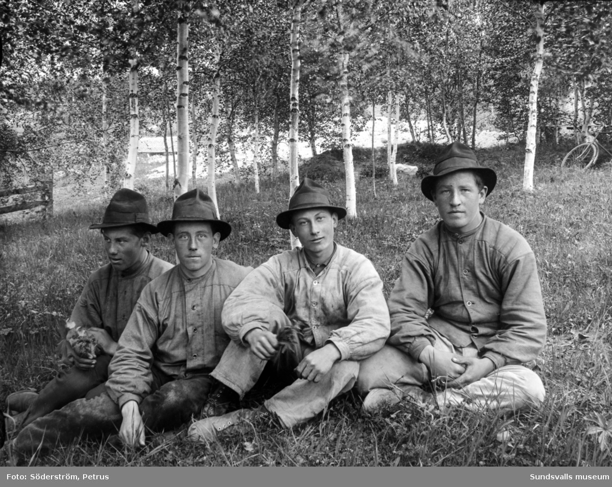 Porträtt på fyra unga män sittande i gräset. Från vänster Einar Björkström, Bror Björkström, Bror Öhlén och Petrus Lindström.