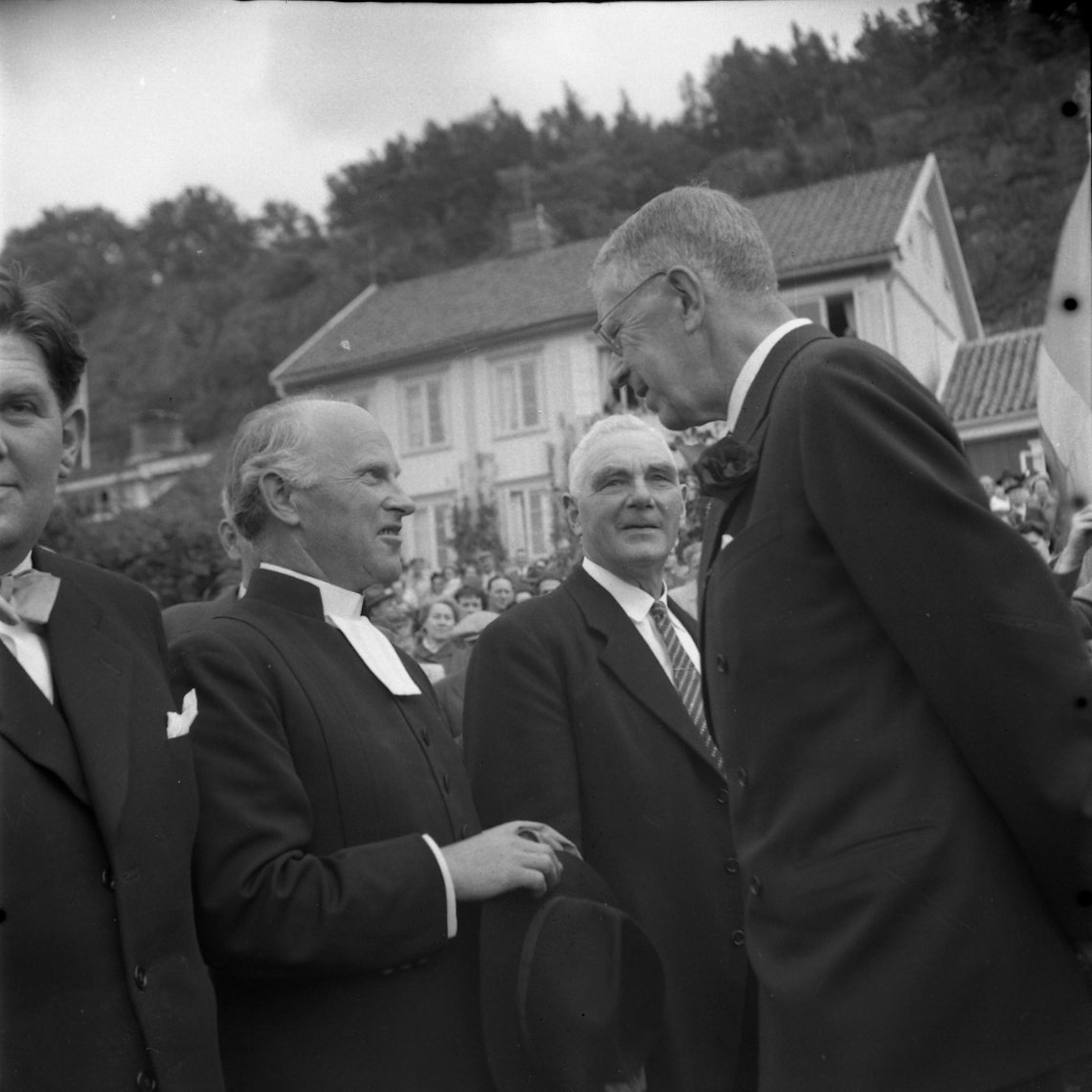 Eriksgata 1954. Kung Gustaf VI Adolf står i Braheparken och samtalar med kyrkoherde Harald Möllerström. Till vänster respektive höger om denne står Sten Roman och Viktor Augustsson.