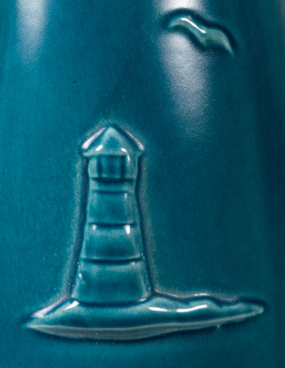 Hög, smal golvvas i keramik med havsmotiv, blåturkos glasyr utvändigt, svart glasyr invändigt. Mindre prickar i glasyren.