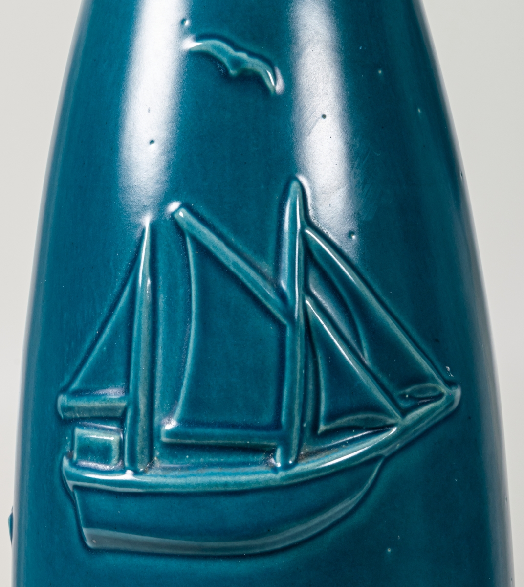 Hög, smal golvvas i keramik med havsmotiv, blåturkos glasyr utvändigt, svart glasyr invändigt. Mindre prickar i glasyren.