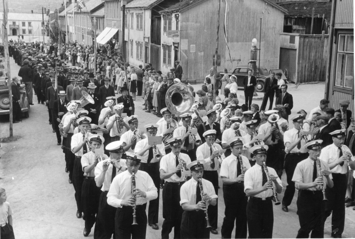 Røros janitsjarorkester i spissen for prosesjonen av ansatte ved Røros kobberverk som går fra Bergskrivergården til kirka i forbindelse med 300-årsjubileet for Røros Kobberverk i 1946