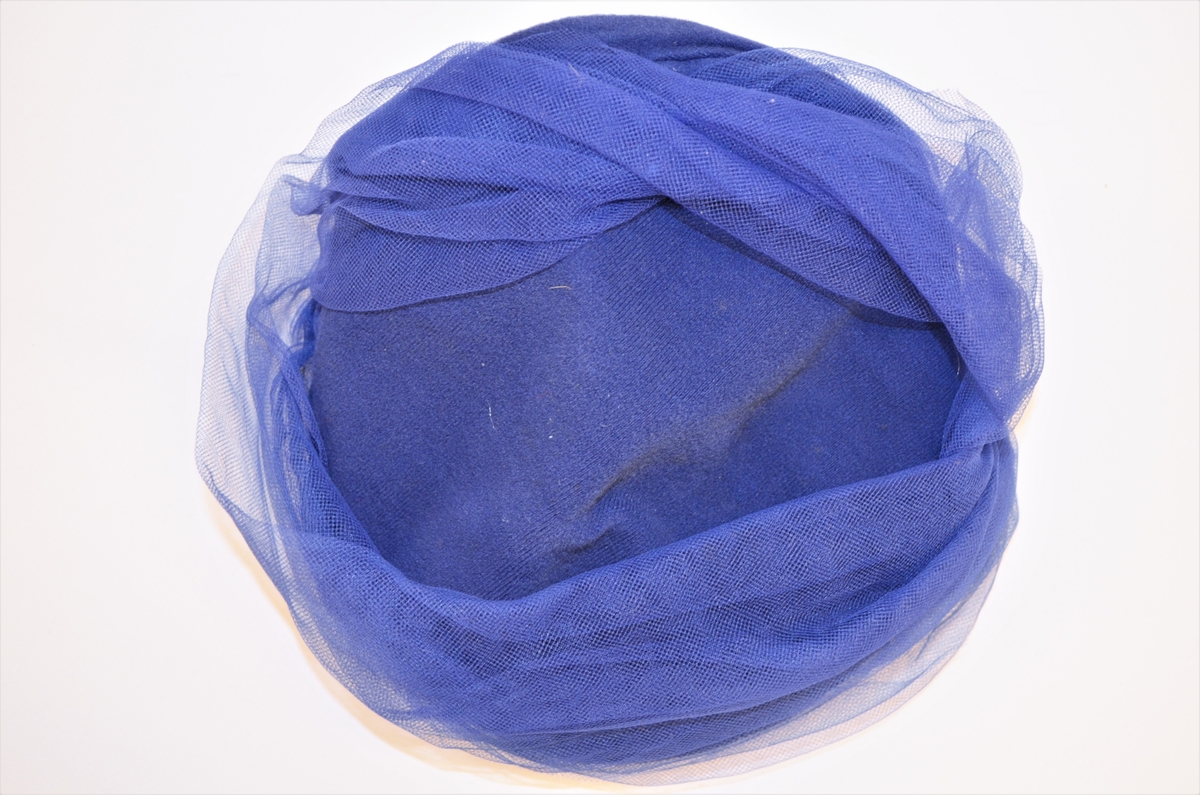 Hatt, i blå filt, fór av svart kunststoff. Pynt av blå tyll(nylon) Merkelapp med pris 168,-