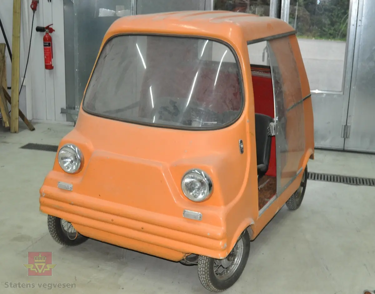 Oransje elektrisk kjøretøy laget i glassfiber. Denne prototypen har bare plass til fører. Rammen er en enkelt ståkonstruksjon og hjulene er av tralletypen. Den hadde konvensjonelt blybatteri og elmotor fra en vaskemaskin.