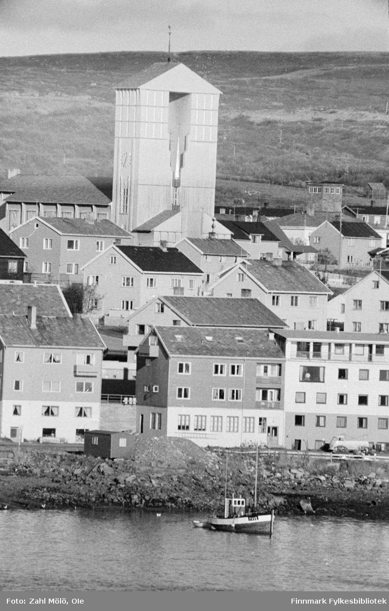 Fiskebåt, hus og kirke i Vadsø, ca. 1970. 