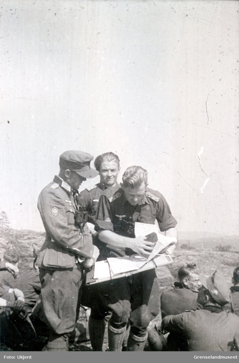 Soldater i felt. Soldaten i venstre hjørne har den karakteristiske Edelweissen på luen de er Østerrikske Gebirgsjägere. På to av de som står, er Edelweisssymbolet synlig på armen. De tre i midten ser på et kart. 