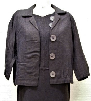 Kjole (a) og tilhørende jakke (b). Kjolen har korte ermer og to store pynteknapper øverst på forsiden. Jakken har tre knapper av samme slag.
