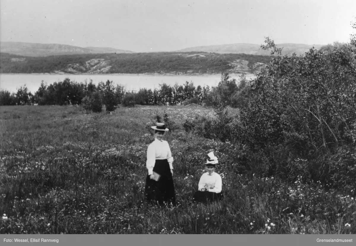 Lærerinne Elise Lilleng og jordmor Annette Lilleng fotografert på Prestegårdsjordet, Kirkenes. Bøkfjorden og Prestøya i bakgrunnen.