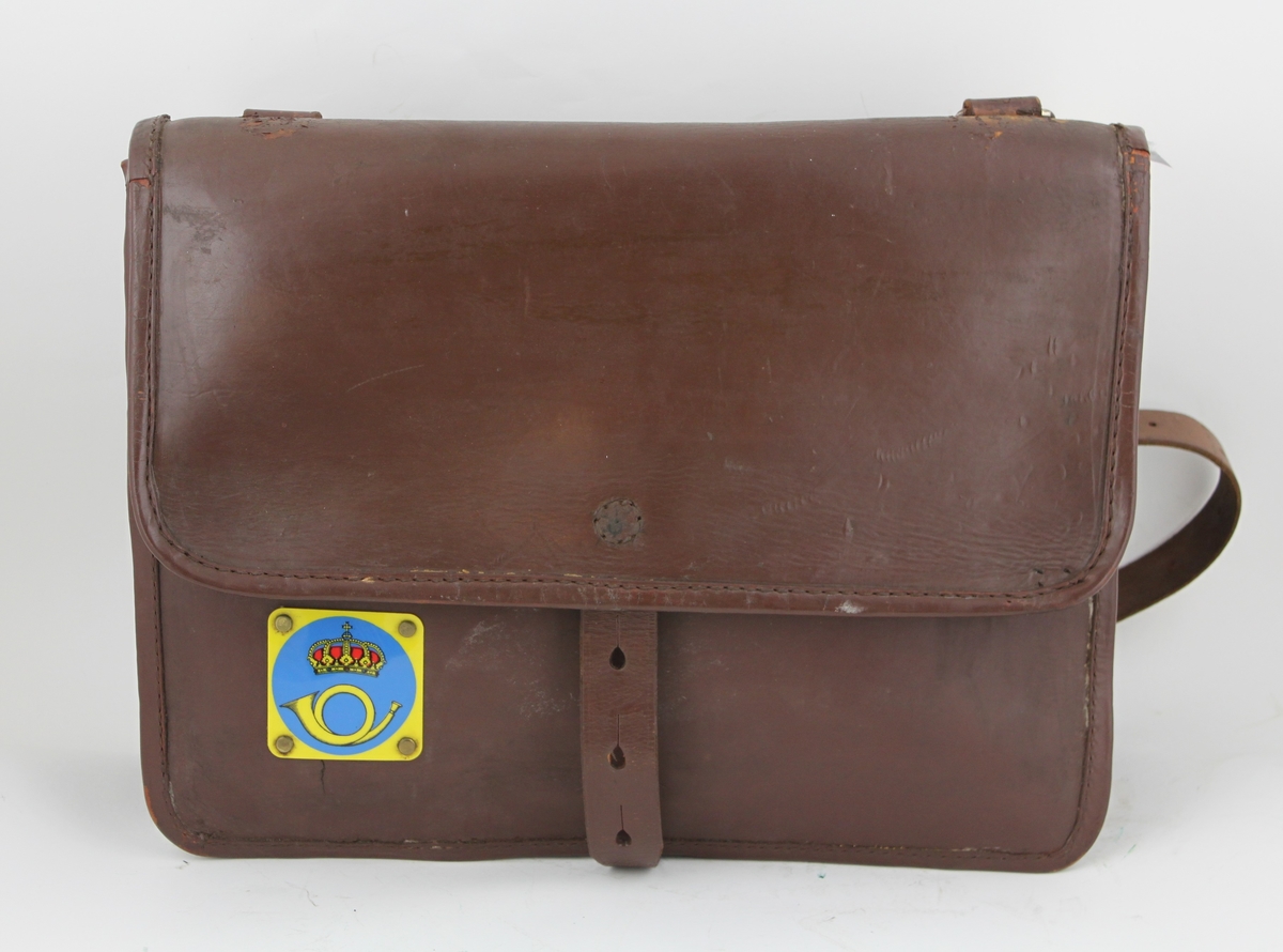 Postväska av läder med axelrem i läder. Skylt av plast med postsymbol modell 1937.