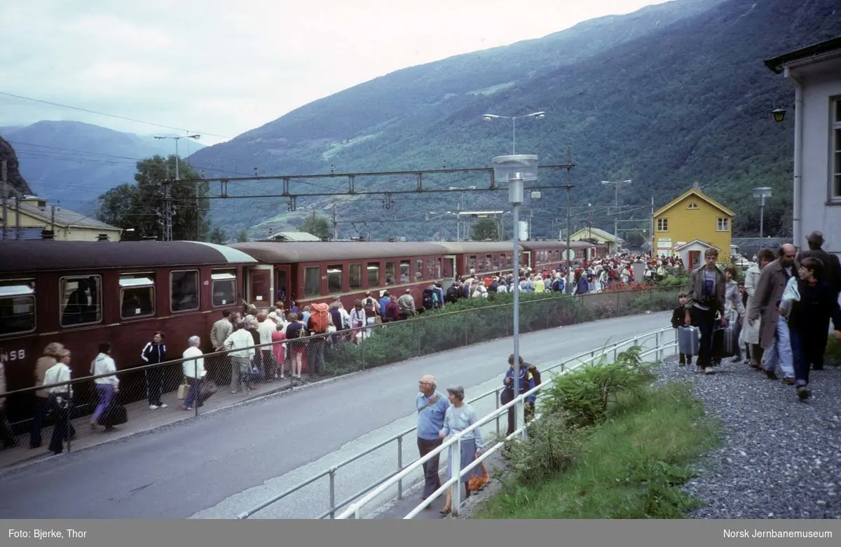 Oversiktsbilde over Flåm stasjon med persontog og mange reisende