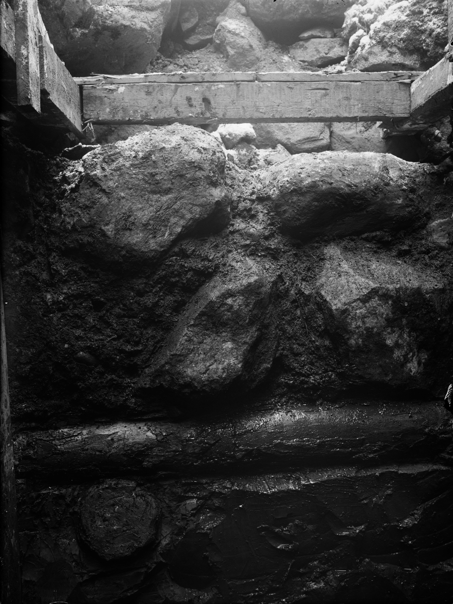 Utgrävning av Helgeandshuset, liggande timmer som bas för stensyll, Uppsala 1925