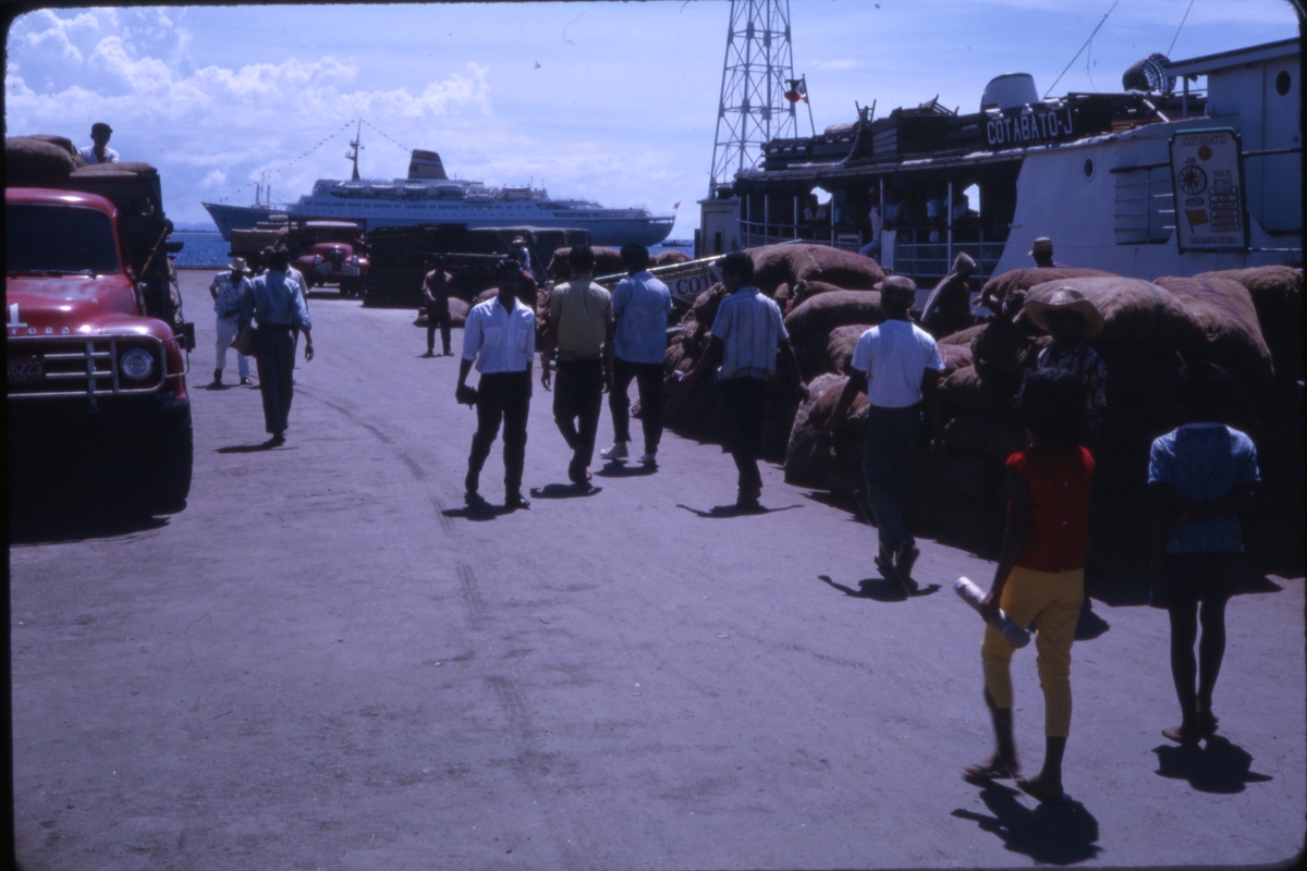 Havneområde på Filippinene, med cruiseskipet 'M/S Sagafjord' i bakgrunnen. 'Sagafjord' Around The World via Africa Cruise 1966.