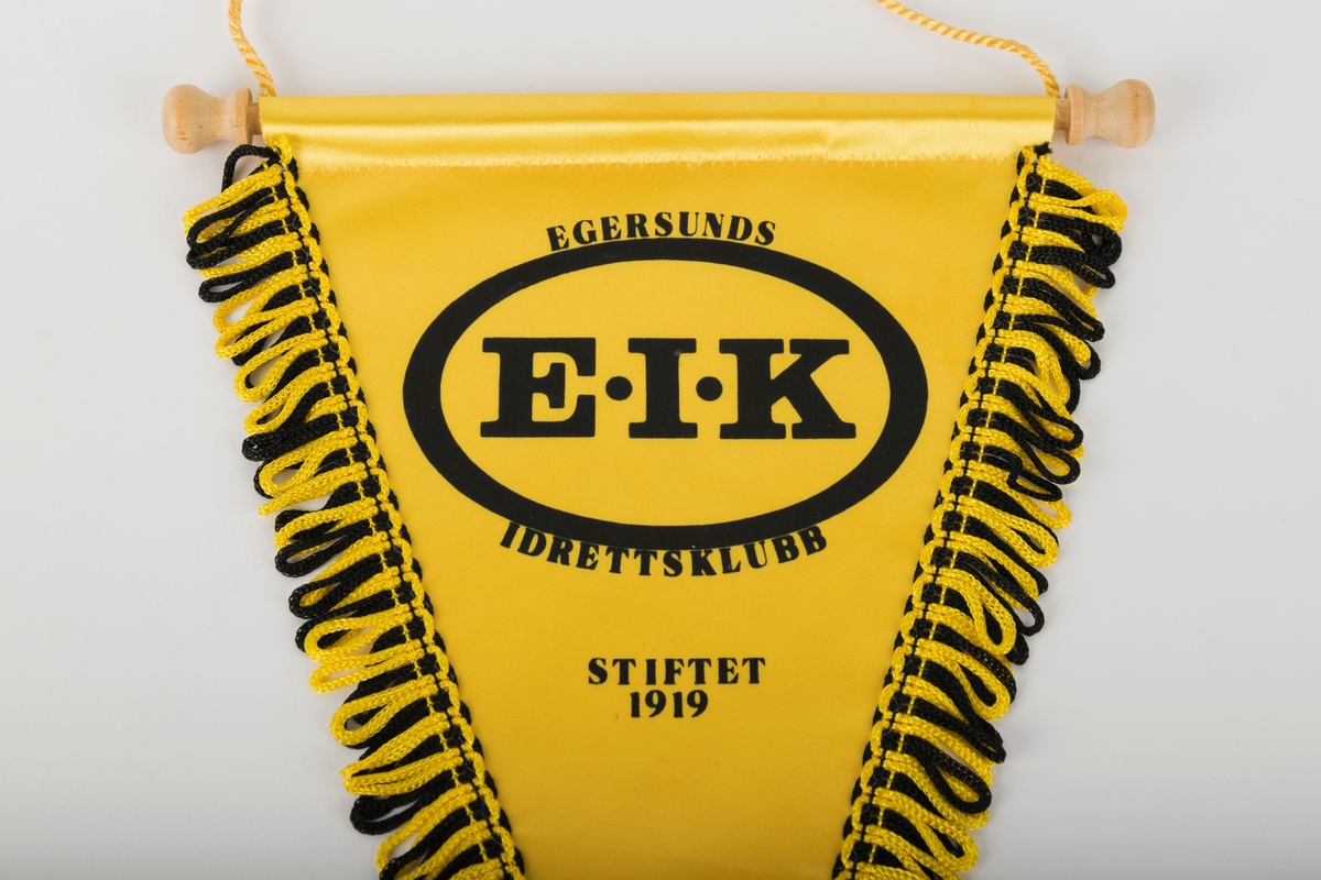 Klubbvimpel for Egersunds Idrettsklubb (EIK). 

Trekantet med frynser. Opphengspinne av tre med tvunnet snor.