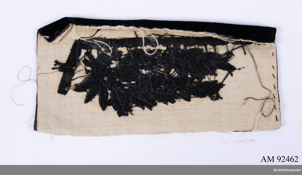 Broderi till krage i svart sammet  med svart broderi i cordonnesilke föreställande två korslagda grenar - en med eklöv och en med lagerblad.