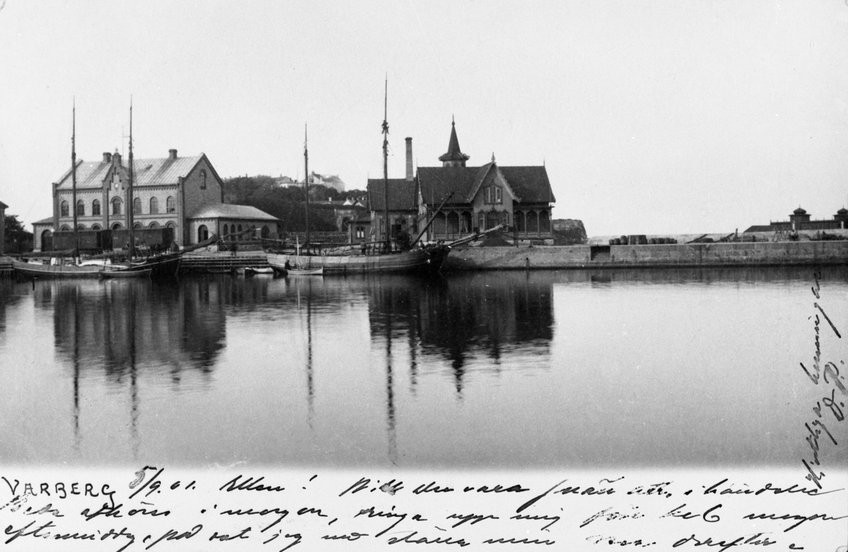 Brevkort daterat 1901. Varbergs hamn med tullhus till vänster och varmbadhuset till höger. I bakgrunden skymtar fästningen och till höger kallbadhuset bakom piren. En järnvägsvagn står framför tullhuset och några skepp ligger vid kajen.
Kortet är daterat 5/8 1901, så fotot är taget senast detta år.