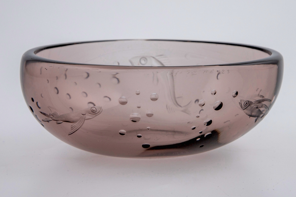 Ovalformet skål i røkfarget gjennomskinnelig glass. Korpus er dekorert med sliping, i form av fisker samt luftbobler.