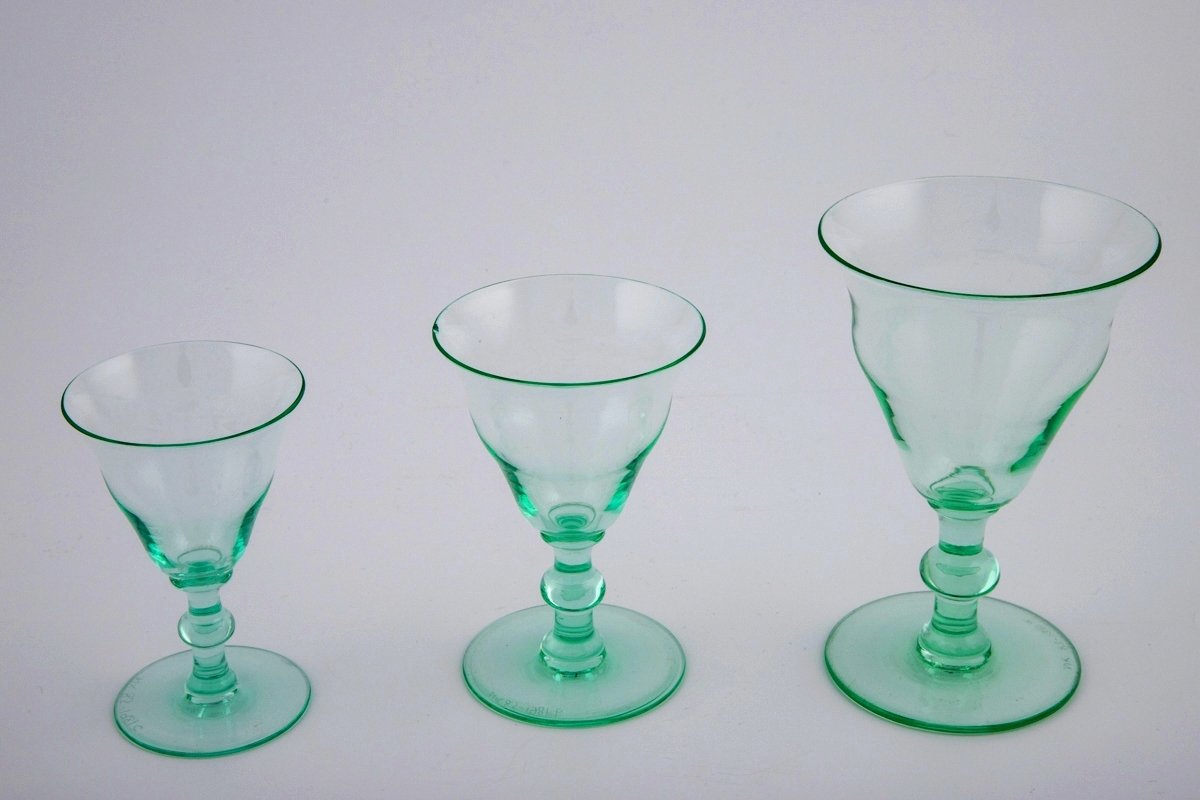 Tre vinglass av gjennomskinnelig glass med grønnlig tone. Buktende klokkeformet kupa, stett med vulst, svakt skrånende fotplate. Glassene er i tre ulike høyder.