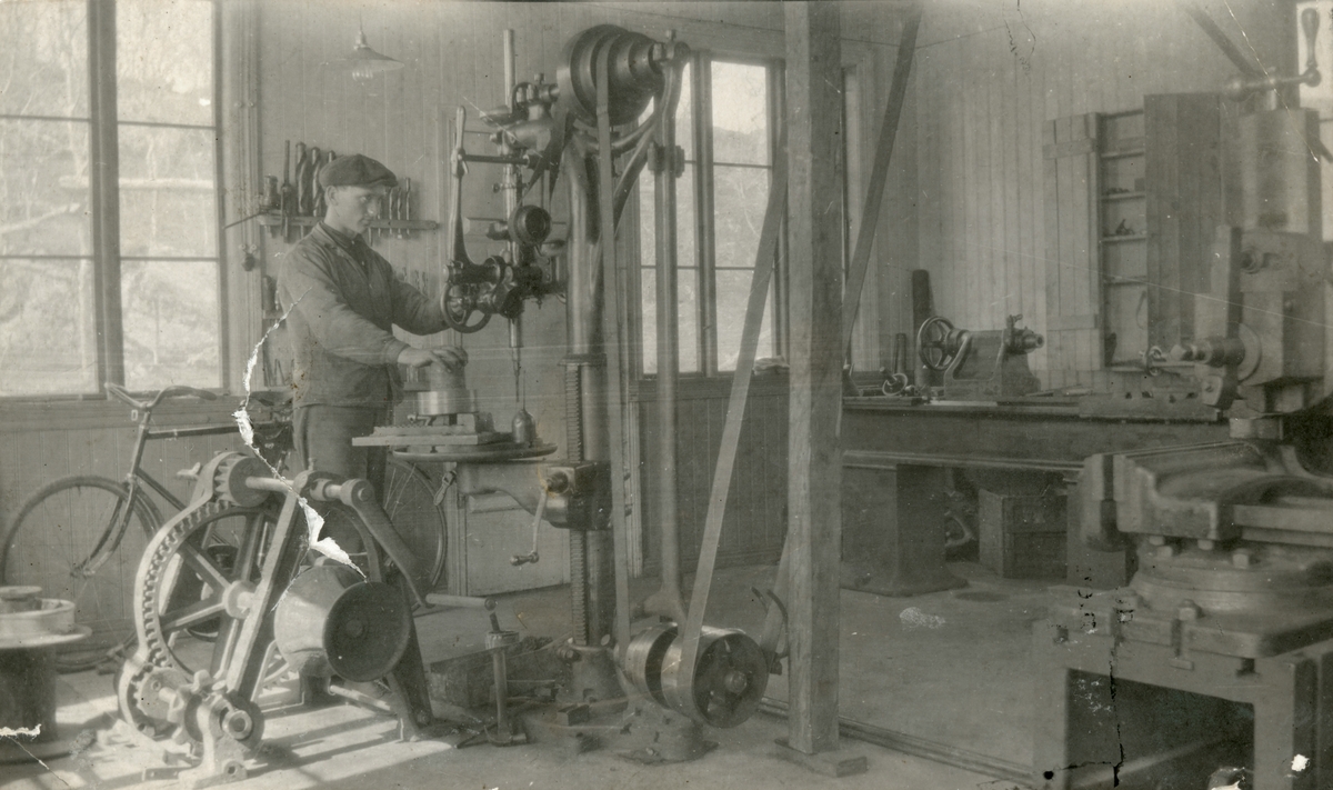 Motiv fra maskinhall ved Ulstein mekaniske verksted. En mann står å jobber ved ei maskin.