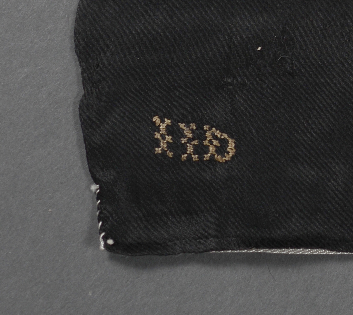 Firkantet tørkle hvor to sider er kantet inn for hånd. Korsstingbroderte initialer "IID" i et av hjørnene.