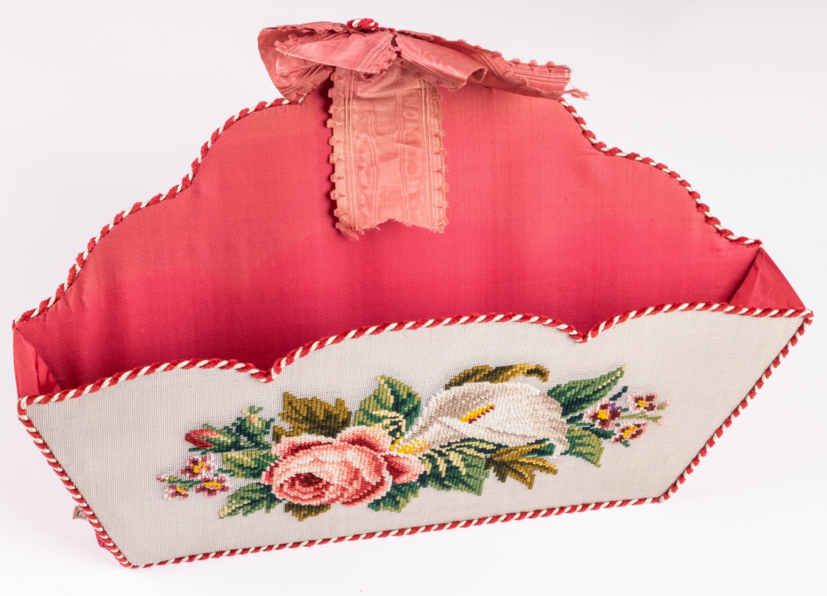 Handskkorg att hänga på väggen, broderad på stramalj, fodrad med rosa siden och kantad med röd och vit snodd.