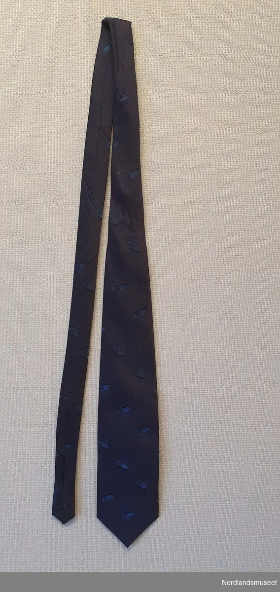 Mørk blått slips med mønster av ovaler i en litt lysere blåfarge.