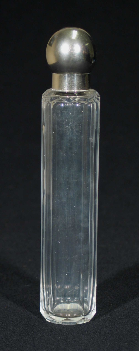 Sylindrisk glassbeholder med rund sølvfarget kork. Den har slipte kanter og en liten hals.